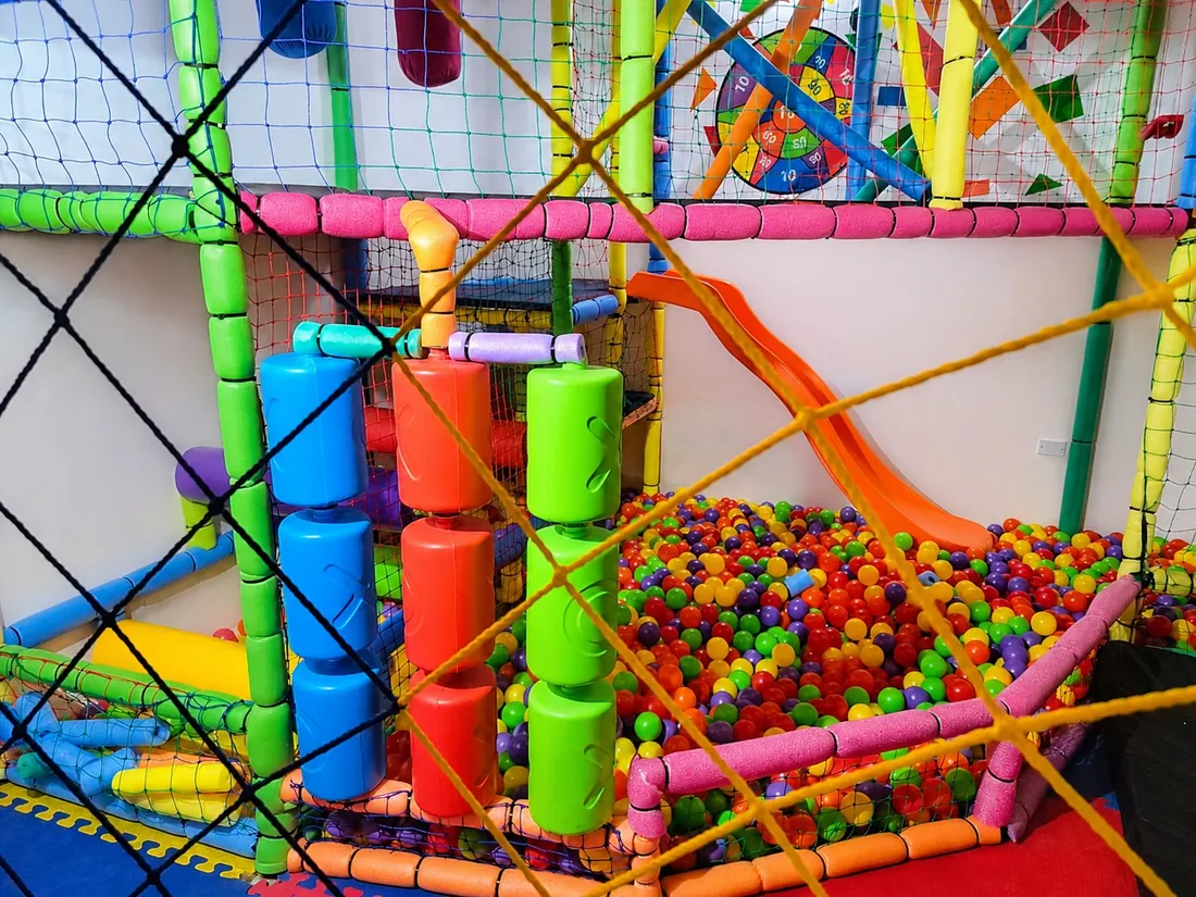 Laberinto con tubos de colores y tobogán naranja sobre la piscina de pelotas